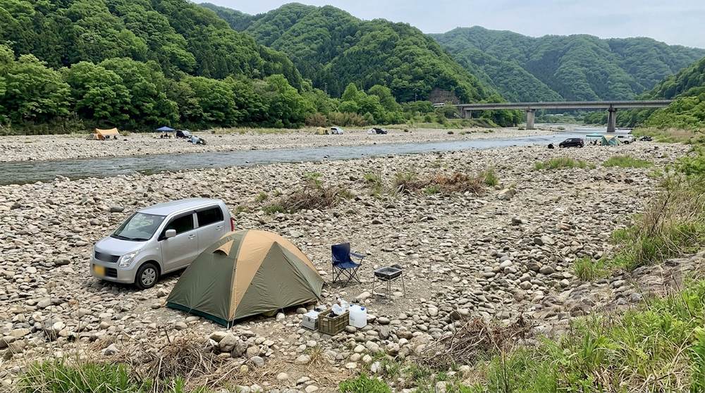 石ころの多い広い河原の奥、川から離れた場所に車を横づけして張ったテント(イメージ)